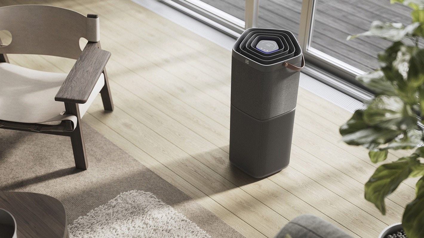 En Electrolux luftrenser står ved siden av en stol i et lyst rom.